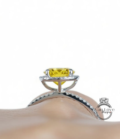 A close-up view of a yellow gemstone, possibly a diamond, set in a silver ring with a halo of smaller diamonds around it.