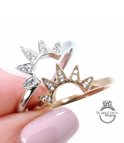A close-up of a person's hand holding two rings, one silver and one gold, with a sun-shaped design on each ring.