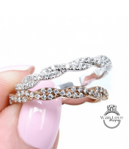 A close-up of a person's hand holding a ring with a pinkish-pink background.