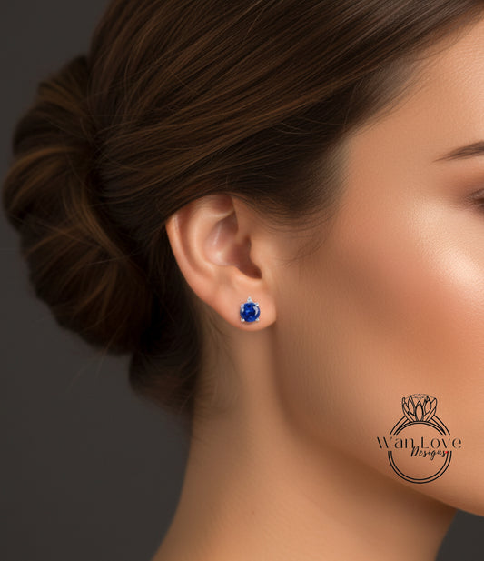 A close-up of a woman's ear with a blue gemstone earring, against a dark background.