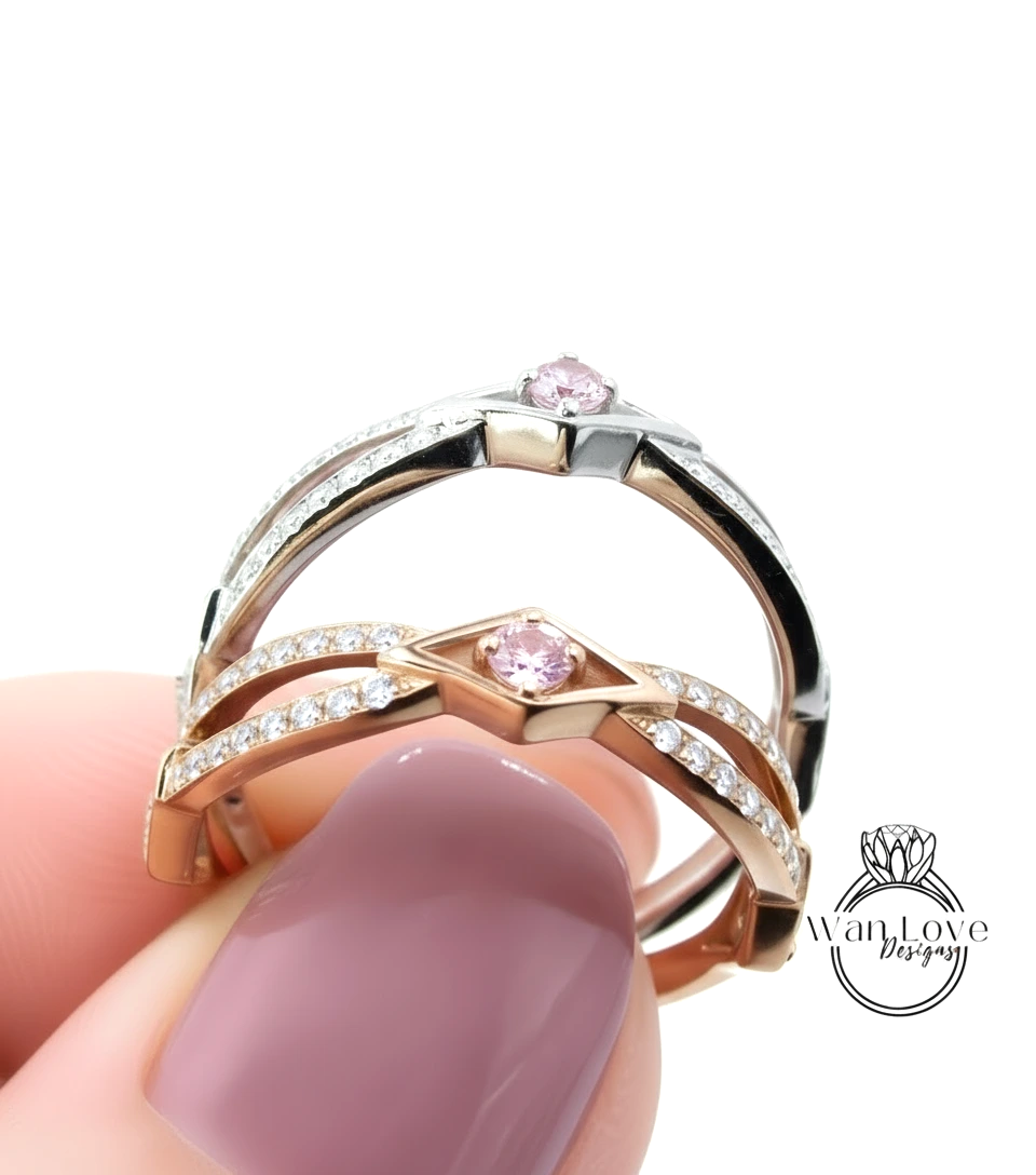 A close-up of a person's hand holding a ring with a pink gemstone, against a white background.