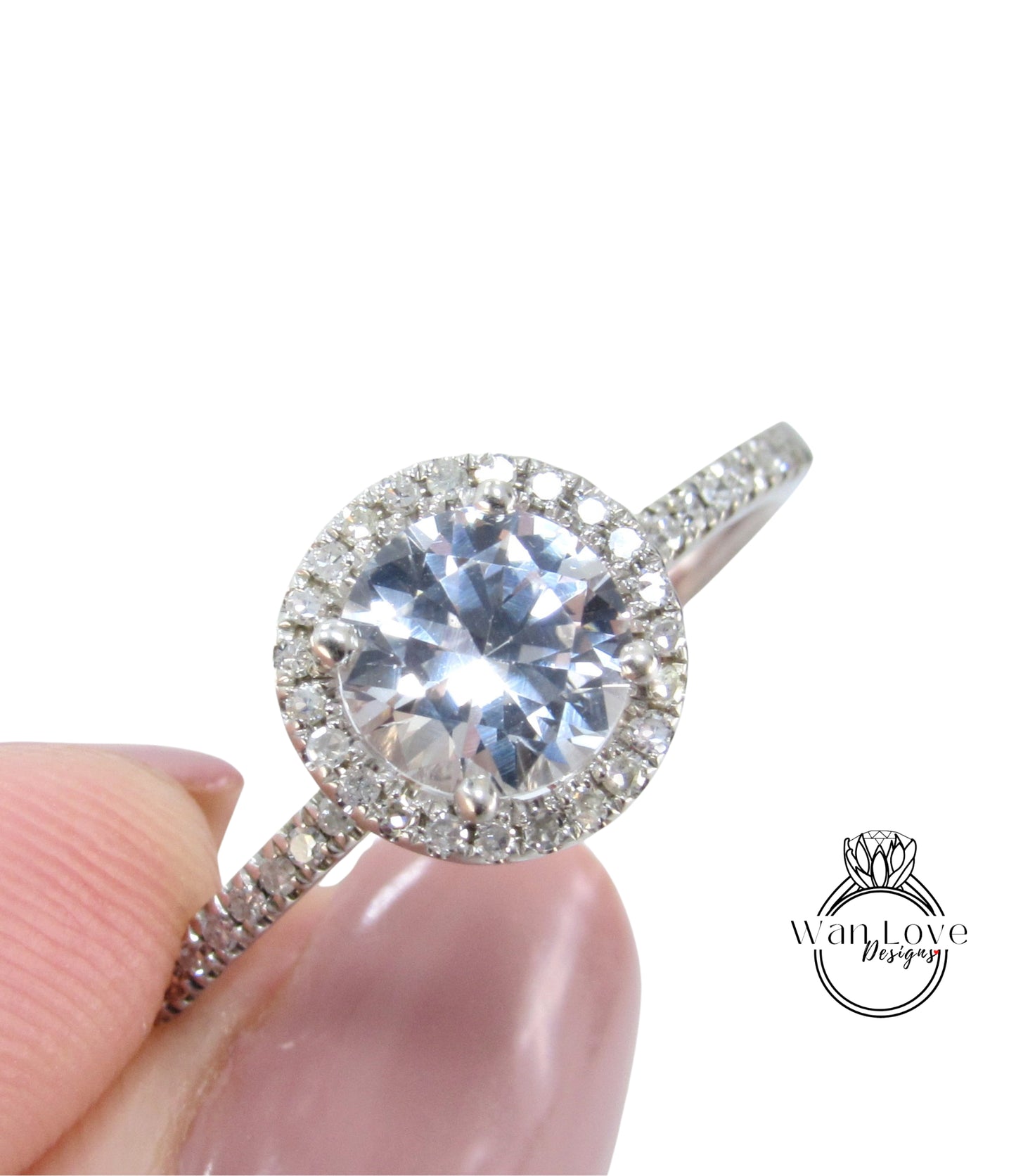 A close-up image of a diamond engagement ring being held in someone's hand, showcasing the sparkling center stone surrounded by a halo of smaller diamonds.