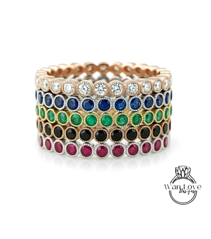 A stack of colorful rings with various gemstones, including diamonds and colored stones, set in a gold or silver band.