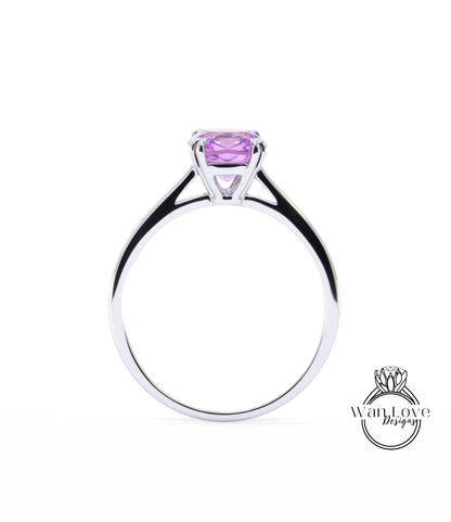 A silver ring with a large purple gemstone, likely a sapphire, set in the center.