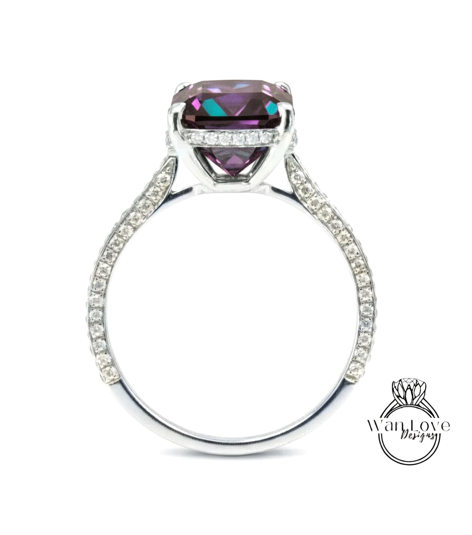 A silver ring with a large purple gemstone, likely a diamond, set in the center.