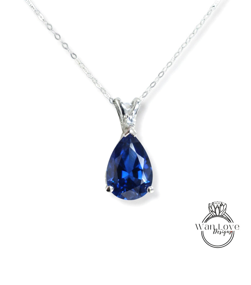 A silver necklace with a large blue gemstone pendant.