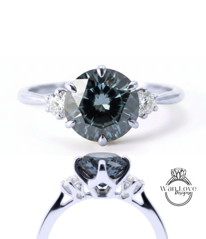 A close-up view of a silver ring with a large, dark blue diamond as the centerpiece. The ring has three smaller diamonds on either side of the central diamond, creating a symmetrical and elegant design.