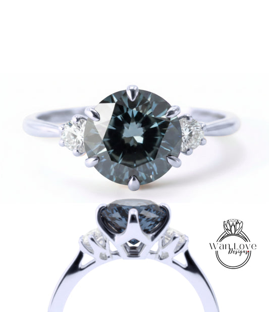 A close-up view of a silver ring with a large, dark blue diamond as the centerpiece. The ring has three smaller diamonds on either side of the central diamond, creating a symmetrical and elegant design.