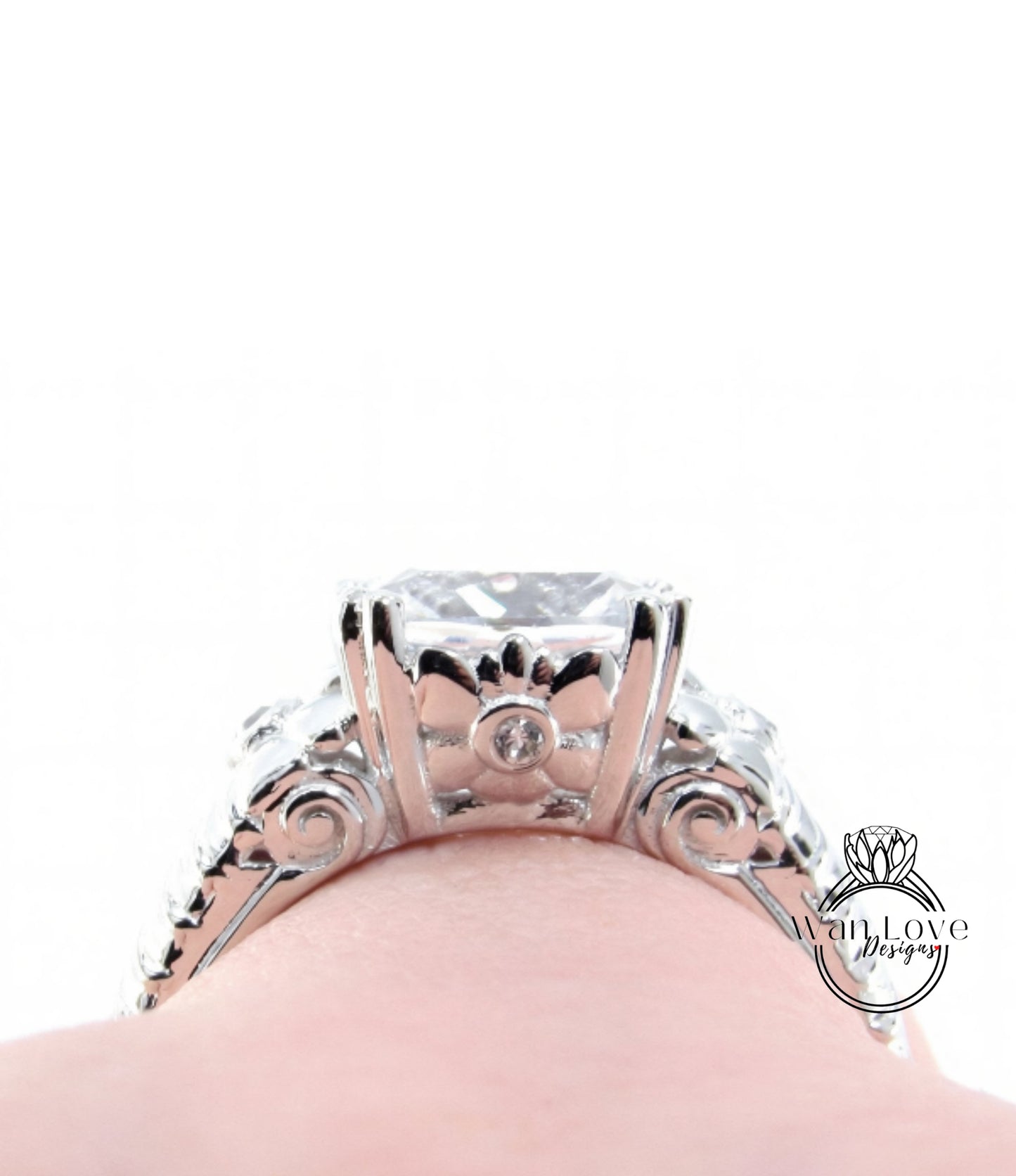 A close-up view of a silver engagement ring with a large central diamond surrounded by smaller diamonds and intricate metalwork.