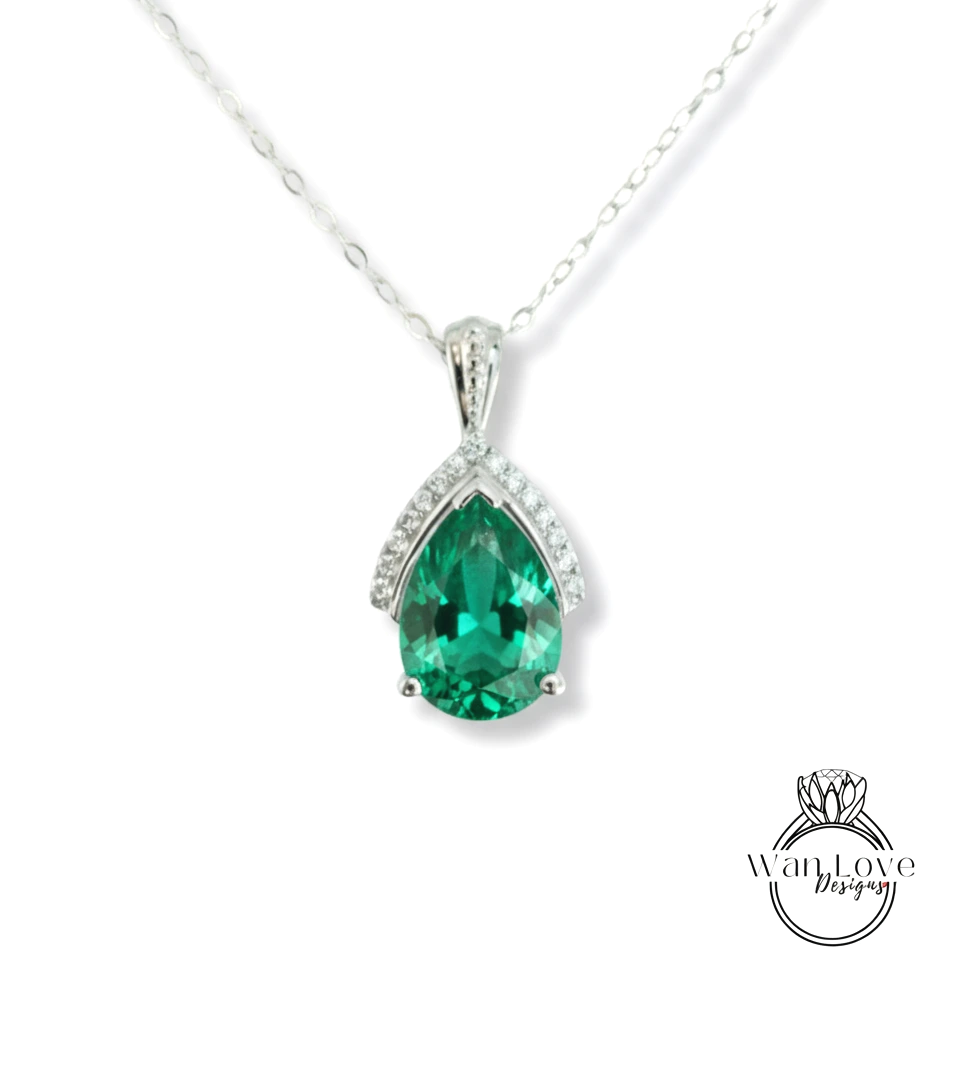 A silver necklace with a large, green gemstone pendant.