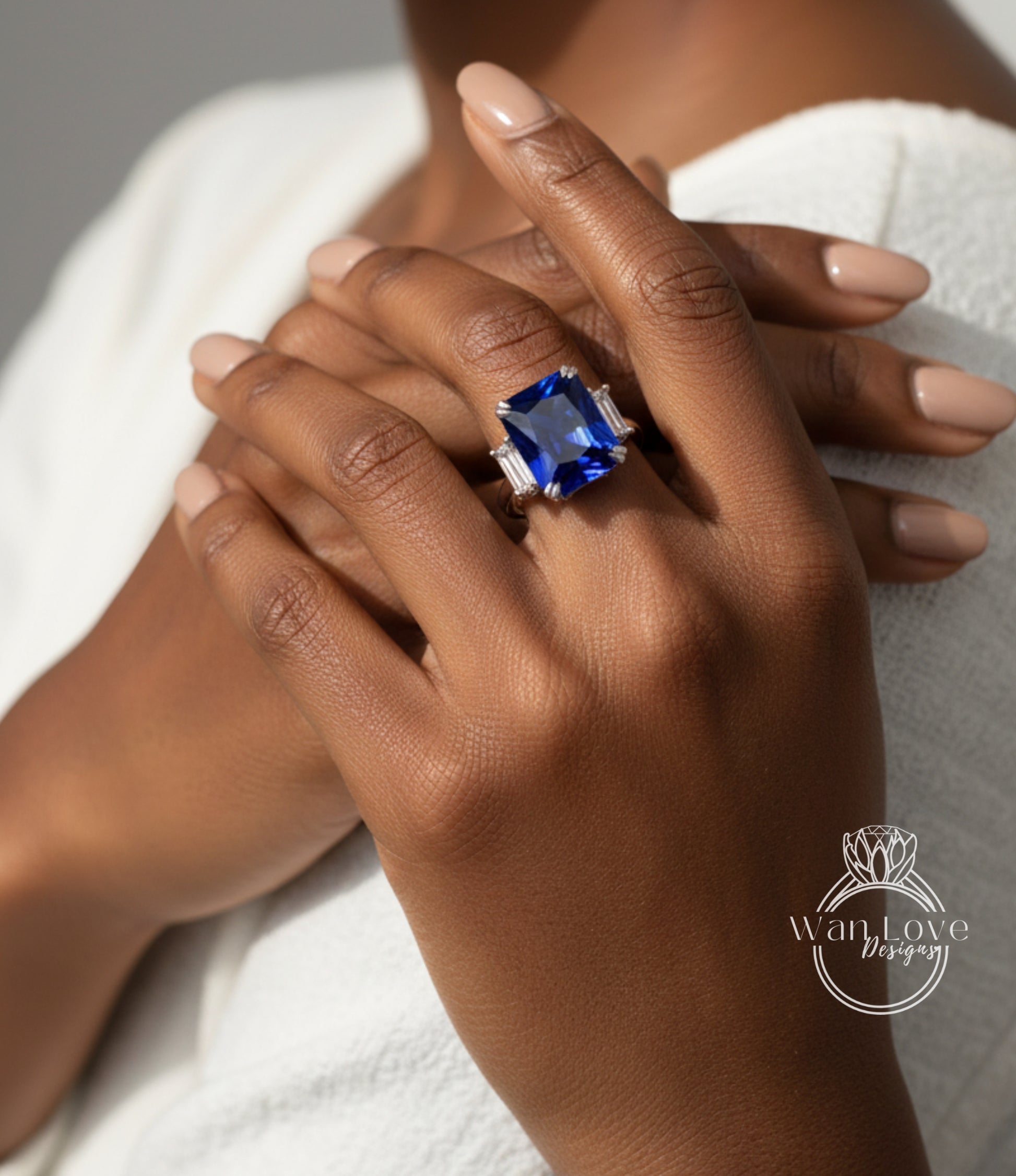 A close-up of a person's hands wearing a large blue gemstone ring.