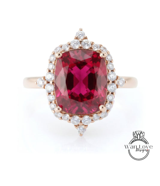 A large, vibrant red gemstone set in a gold ring with a halo of smaller diamonds around it.