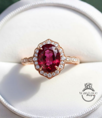 A close-up image of a beautiful pink garnet ring with a halo of diamonds set in a gold band, displayed in a white jewelry box.