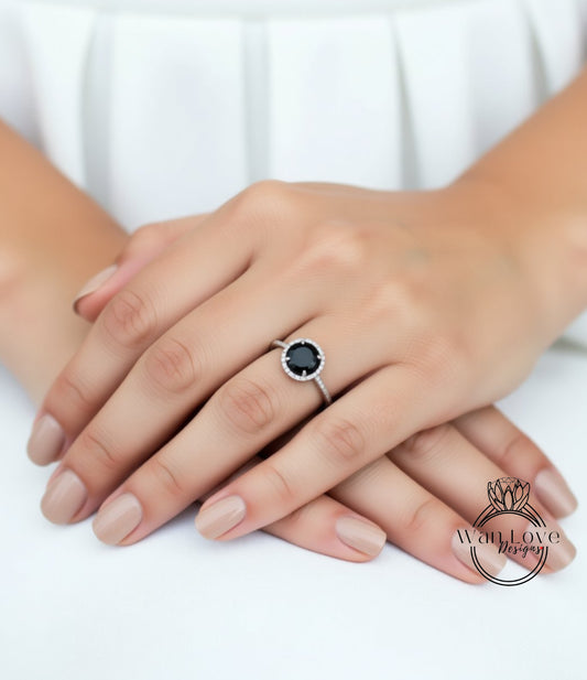 A close-up of a person's hands wearing a ring with a large black gemstone.