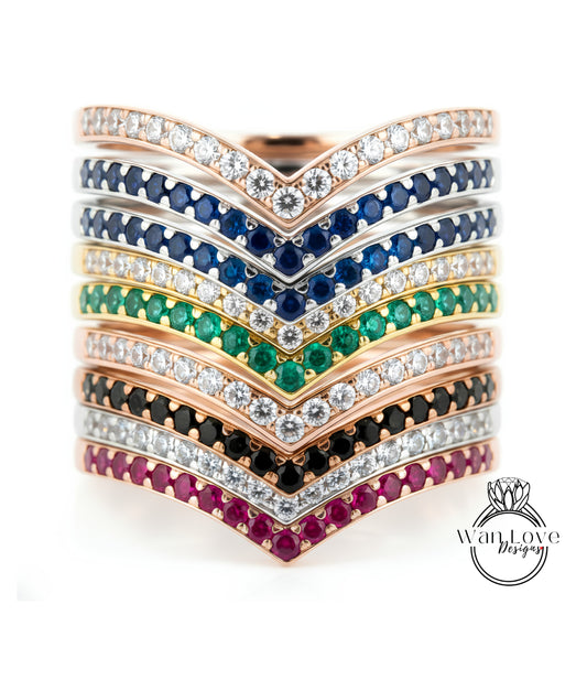 A stack of rings with various colored gemstones and diamonds set in a v-shaped design.