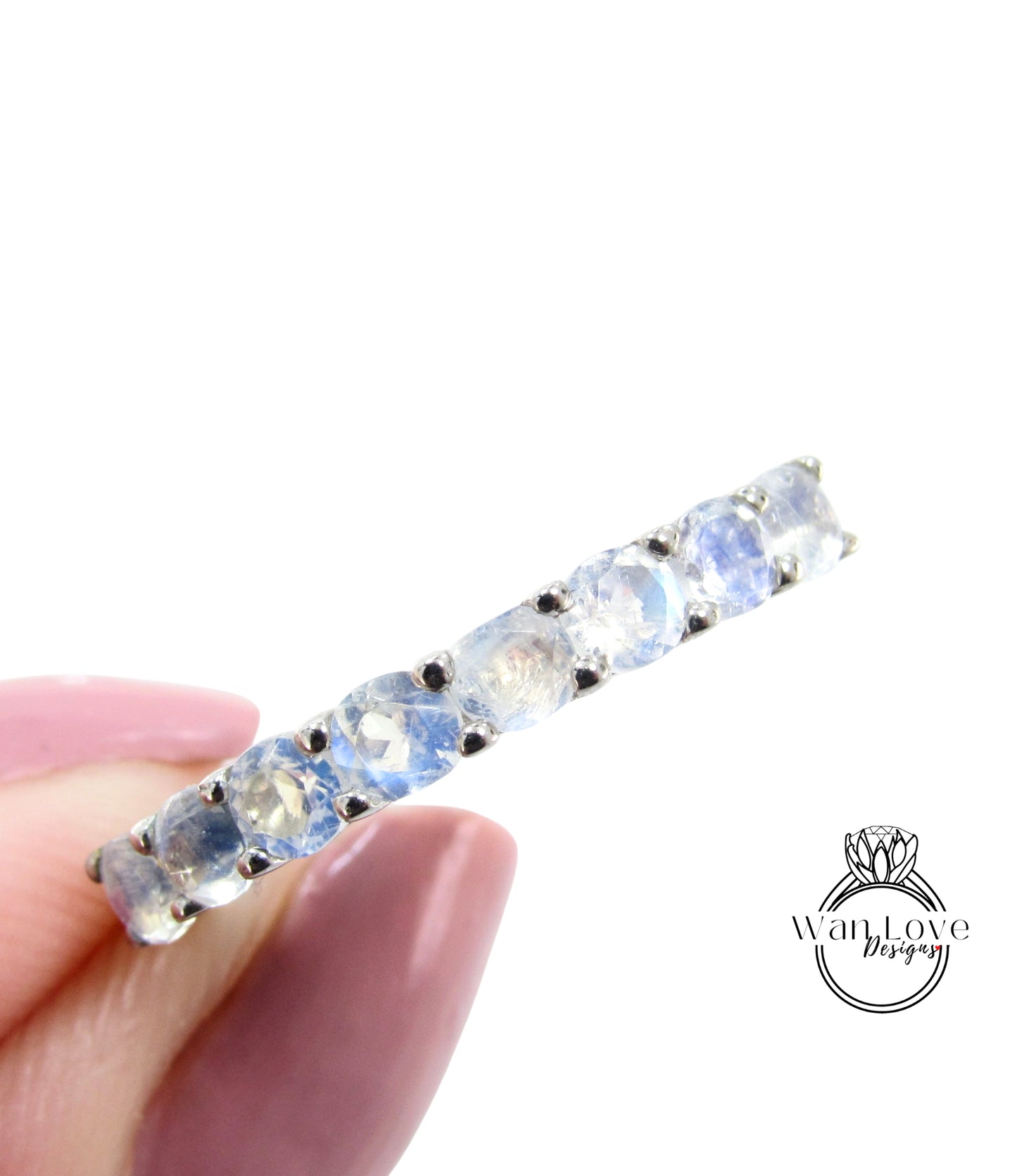 A close-up image of a person's hand holding a ring with a row of blue stones or gemstones.
