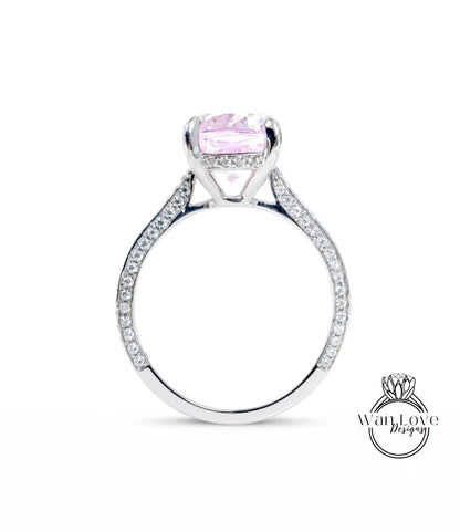 A silver engagement ring with a large pink gemstone, set in a diamond-encrusted band.