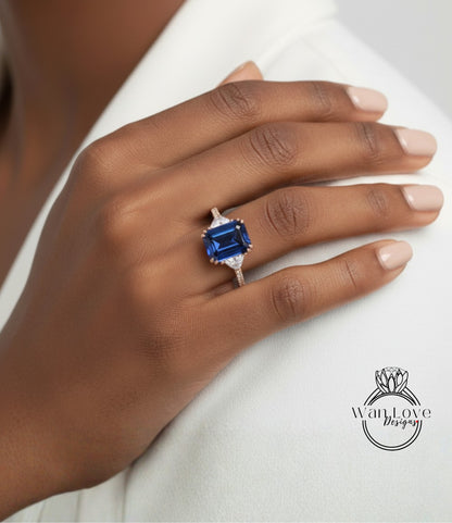 A close-up of a hand wearing a blue gemstone ring on the ring finger.