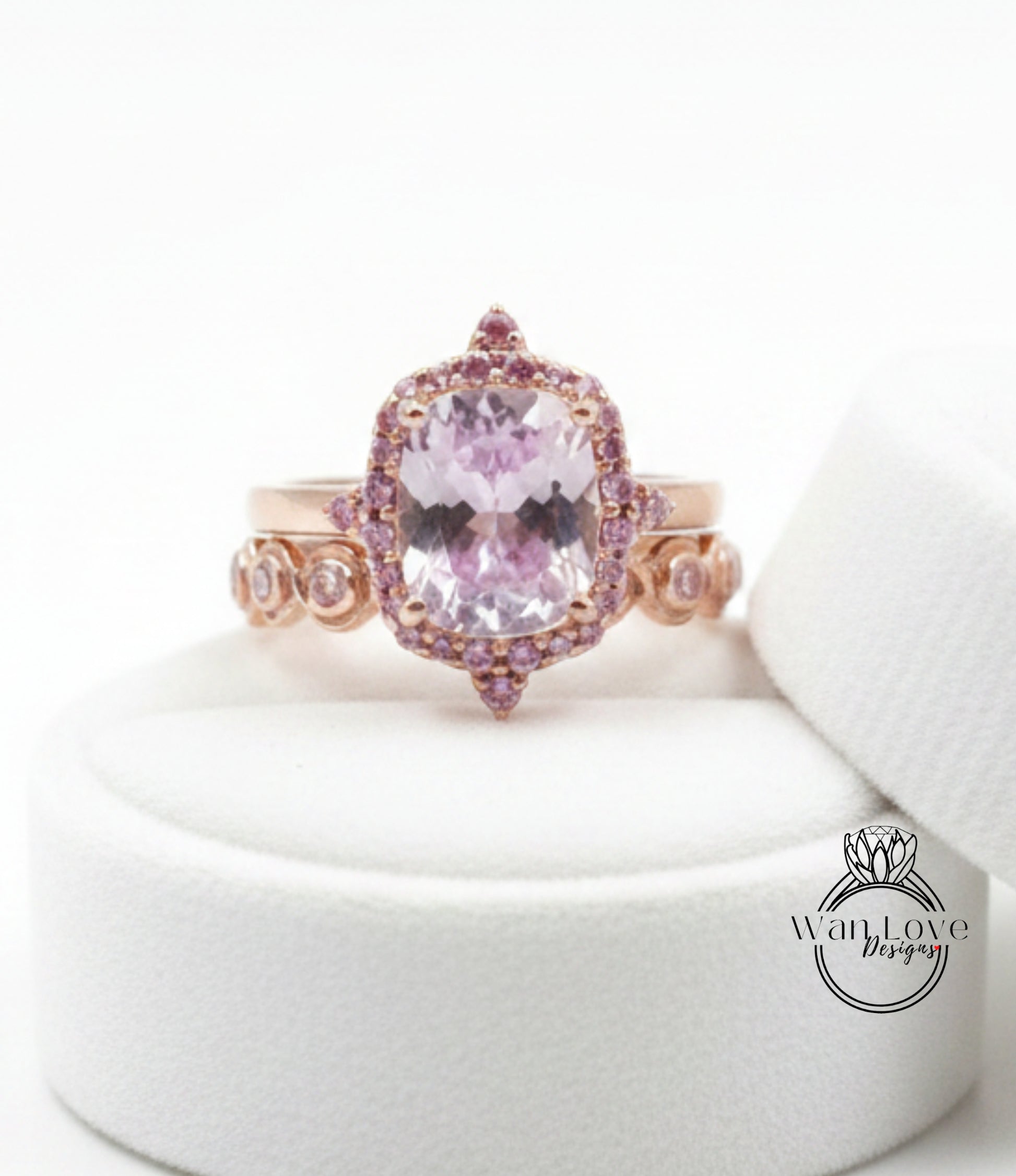 A pink gemstone ring with a large central stone surrounded by smaller stones and a halo of smaller stones on the sides.