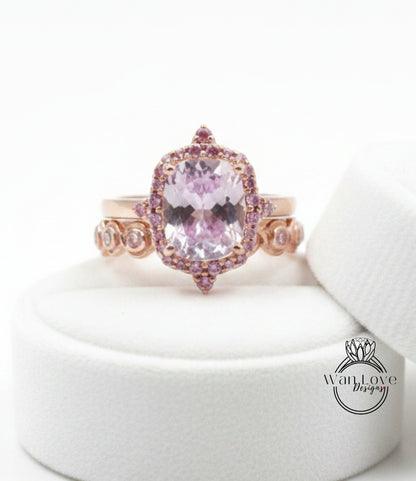 A pink gemstone ring with a large central stone surrounded by smaller stones and a halo of smaller stones on the sides.