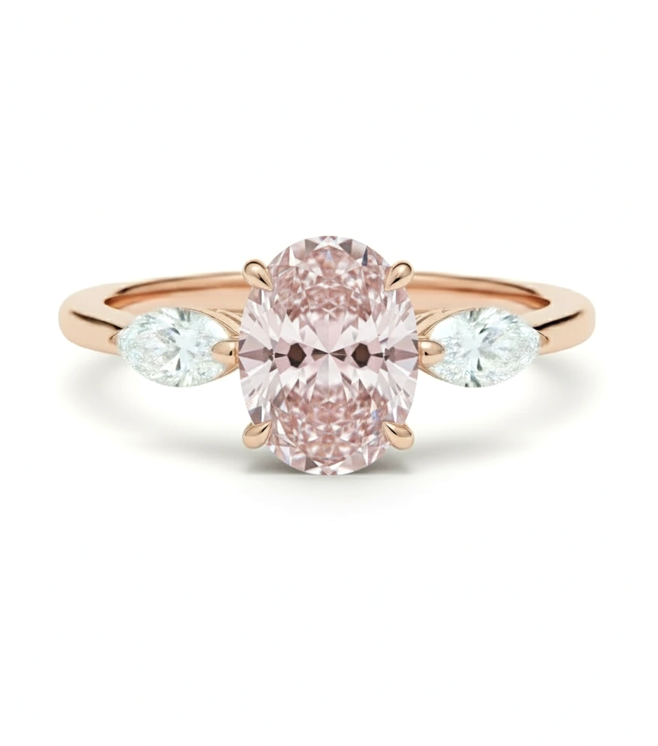 A rose gold engagement ring with a large oval-shaped pink diamond set in the center, flanked by two smaller diamonds on either side.