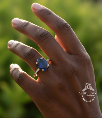 A close-up of a hand wearing a ring with a large blue gemstone, set in a gold band.