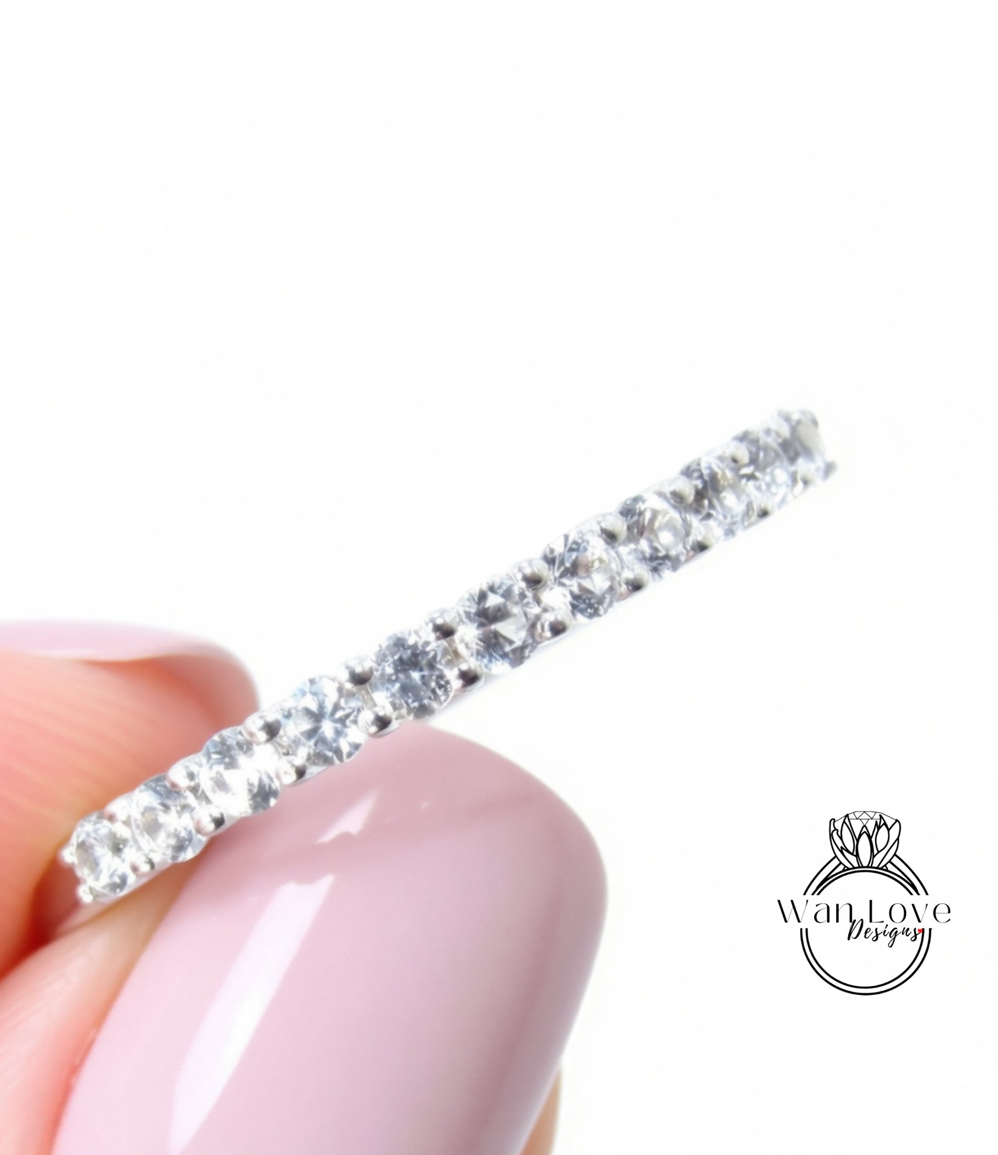 A close-up of a person's hand holding a diamond-encrusted ring against a white background.