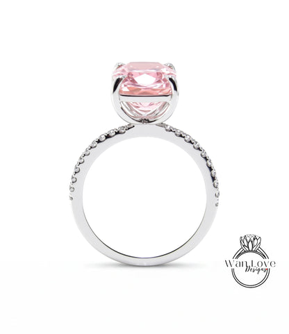 A silver ring with a large pink gemstone, likely a diamond, set in the center.