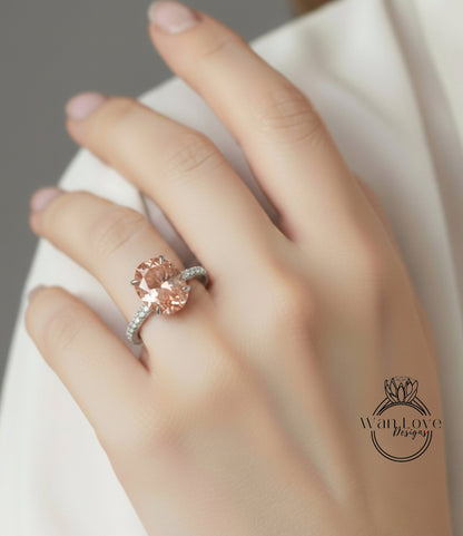 A close-up of a person's hand wearing a large, oval-shaped pink diamond engagement ring.