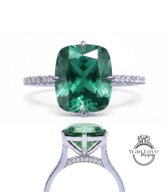 A large, green gemstone engagement ring with a silver band and small diamonds.