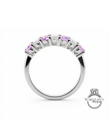 A silver ring with a row of pink gemstones, including diamonds, set in a band.