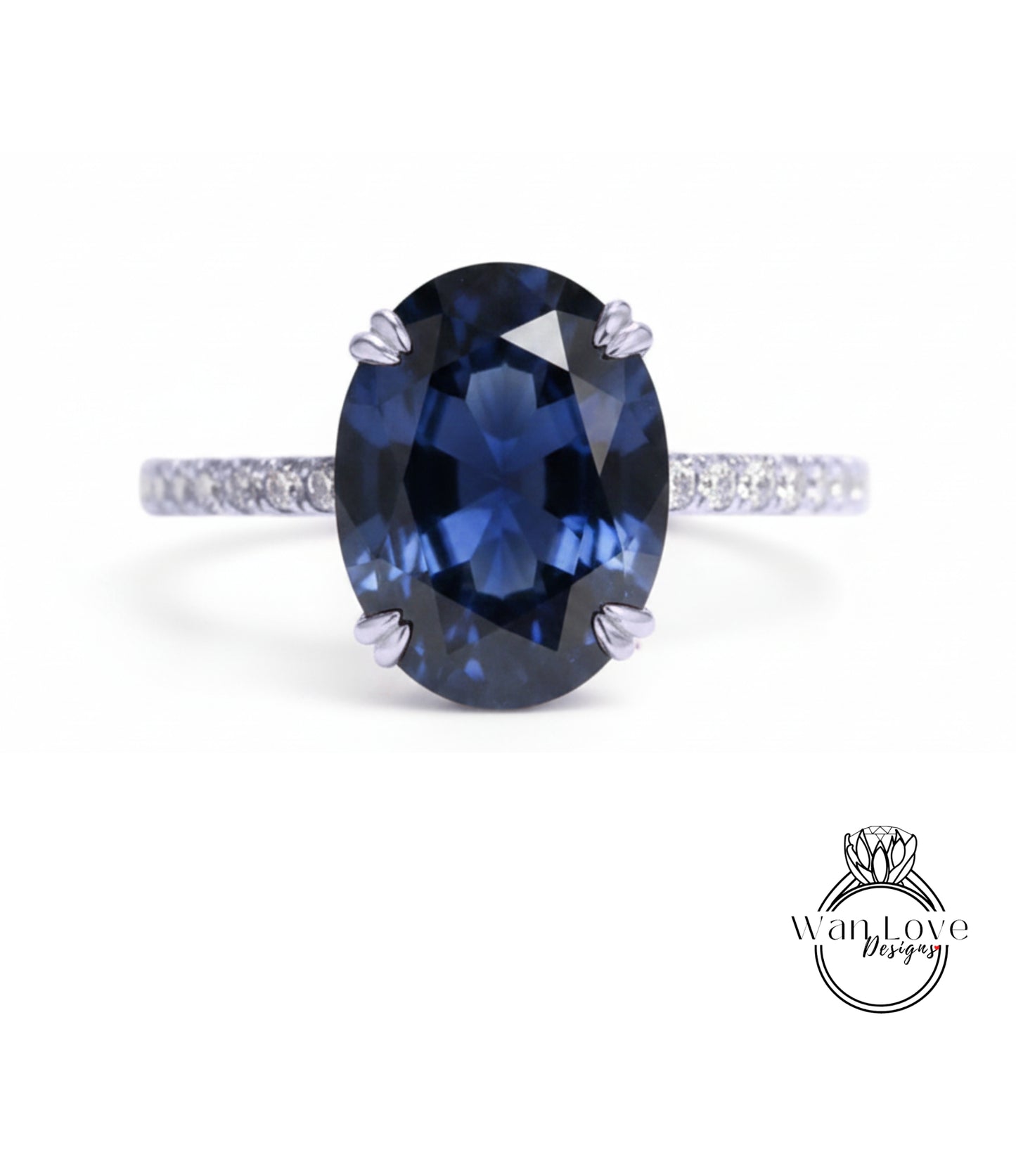 A close-up of a blue sapphire engagement ring with a diamond band.