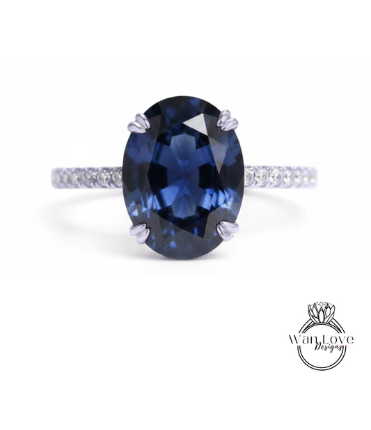 A close-up of a blue sapphire engagement ring with a diamond band.
