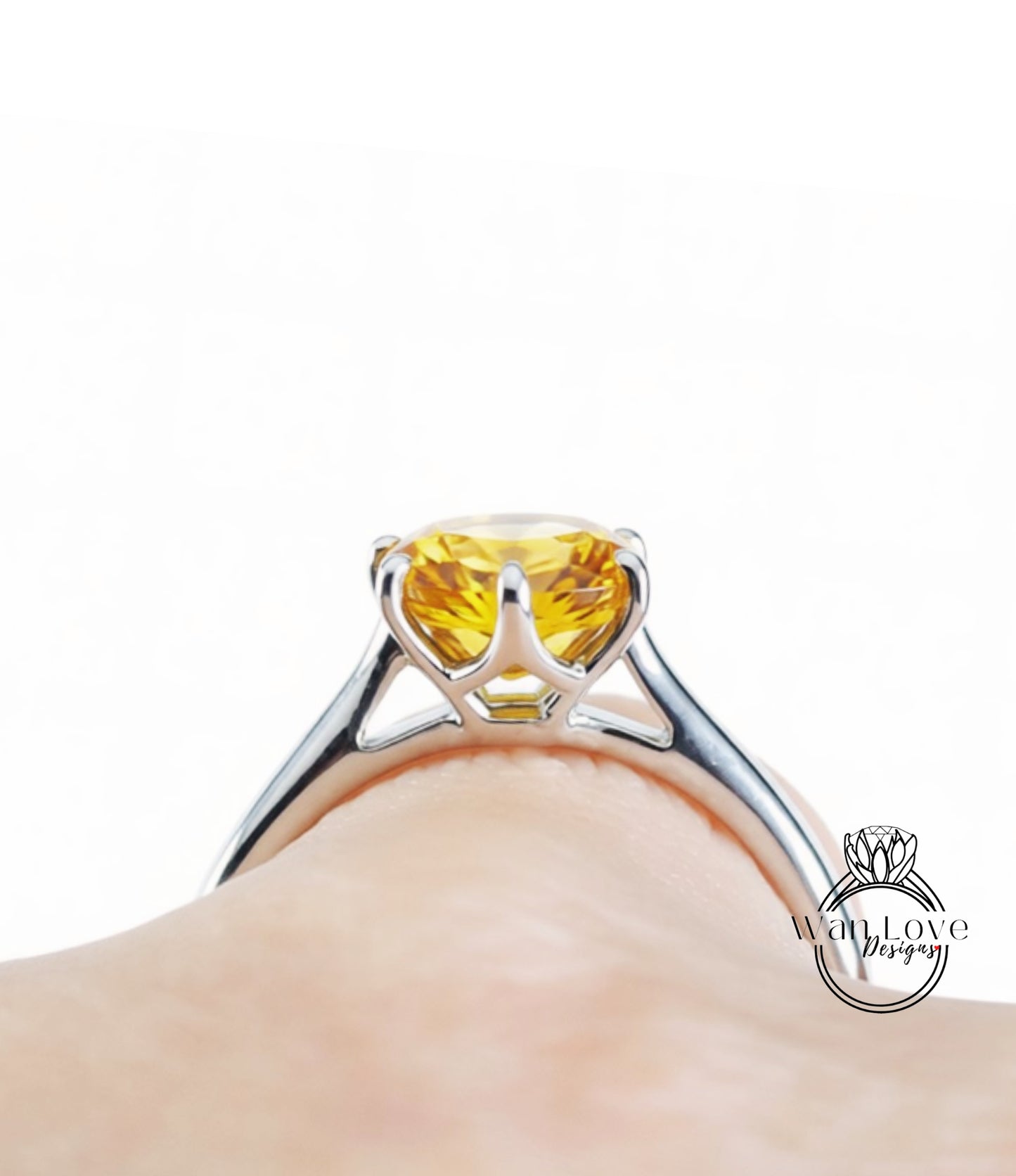 A close-up view of a silver ring with a yellow gemstone, likely a diamond, set in a metal band.