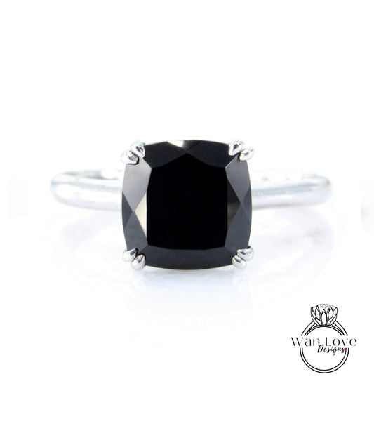 A close-up image of a silver ring with a large, square-cut black diamond as the centerpiece.