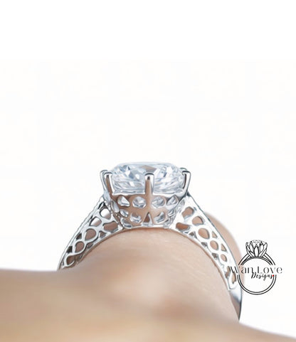 A close-up view of a diamond engagement ring on a person's hand, showcasing the intricate metalwork and the large central diamond.