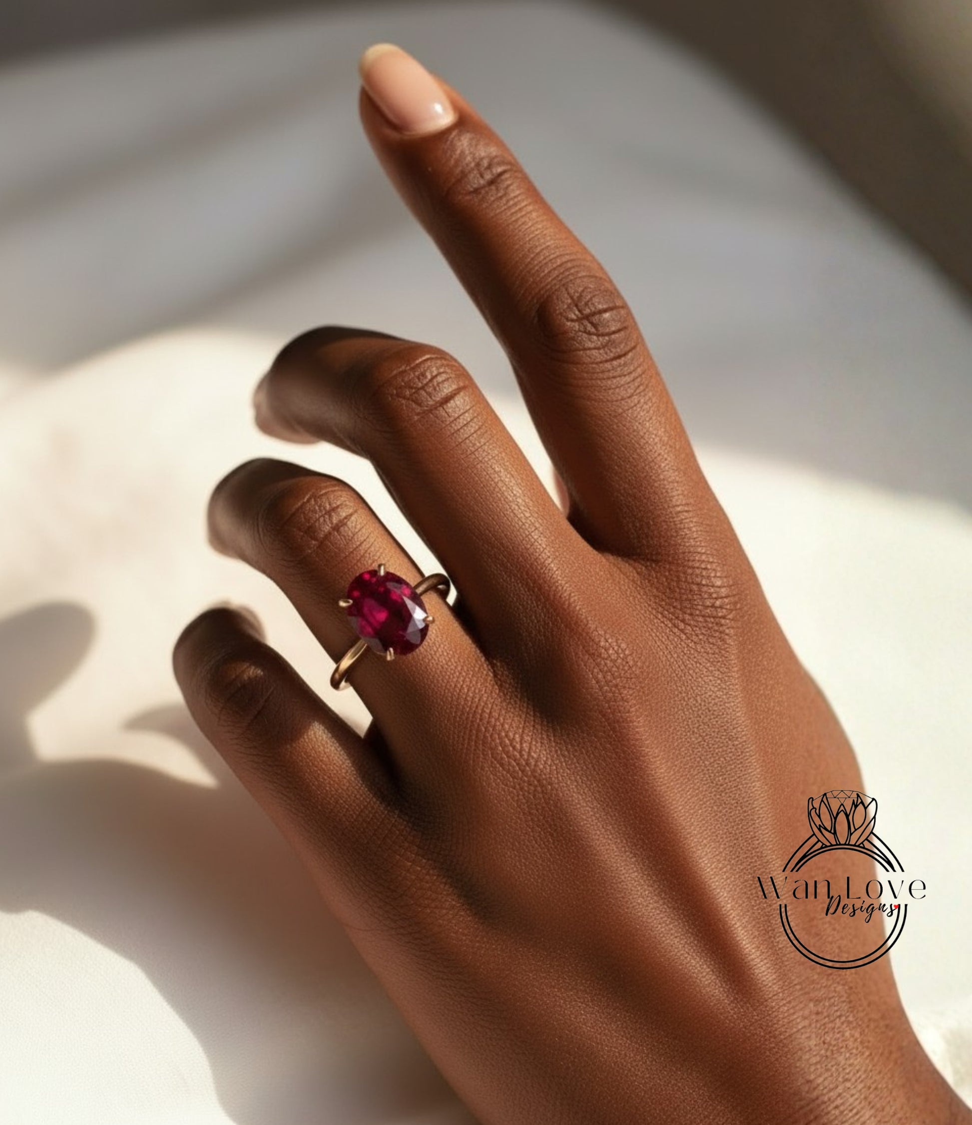 A close-up of a hand wearing a gold ring with a large, deep red gemstone.