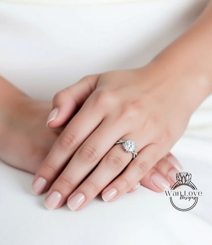 A close-up of a hand wearing a diamond engagement ring, resting on a white surface.
