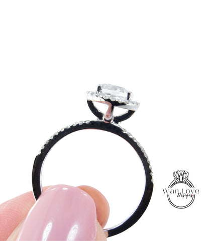 A close-up of a person's hand holding a diamond engagement ring with a large central diamond surrounded by smaller diamonds on the band.
