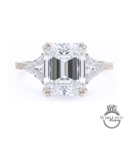 A large, clear diamond engagement ring with a prominent central diamond surrounded by smaller diamonds on either side.