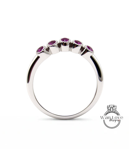 A silver ring with a row of five purple gemstones set in the center.