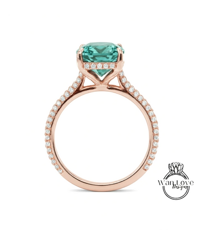 A rose gold engagement ring with a large, square-cut green gemstone set in the band, surrounded by small diamonds.