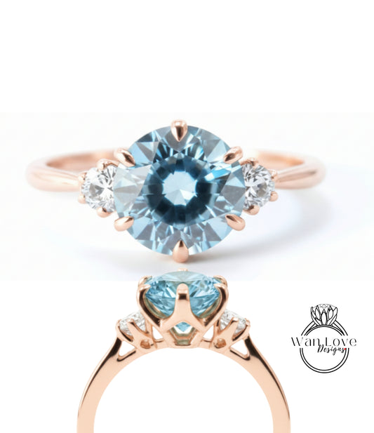 a beautiful blue gemstone ring with a gold band and three smaller diamonds.