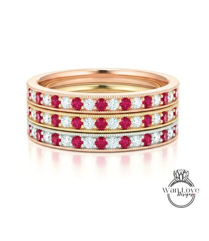 A gold ring with three concentric bands of red and white diamonds.