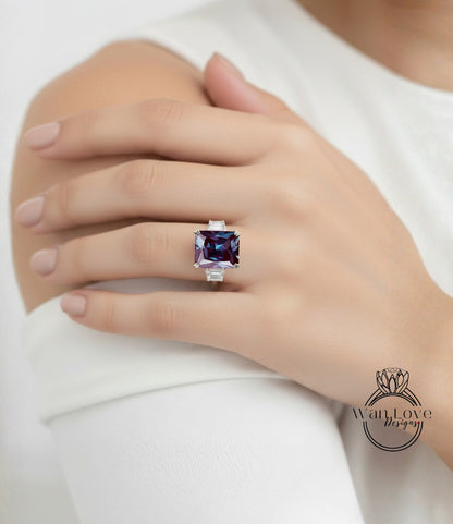 A close-up of a person's hand wearing a large, purple gemstone ring on the ring finger.