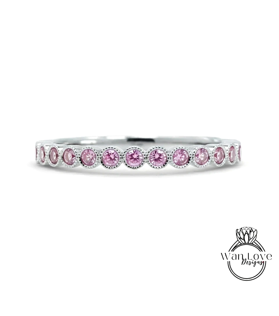 A silver band ring with a row of pink gemstones, likely diamonds, set in a row.