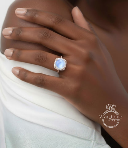 A close-up of a hand wearing a ring with a blue gemstone, resting on a white fabric.