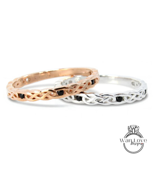 Two rings with intricate designs, one in gold and the other in silver, both featuring black stones.