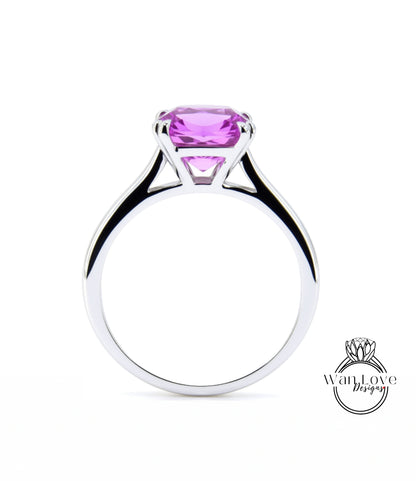 A silver ring with a large, vibrant pink gemstone set in the center.