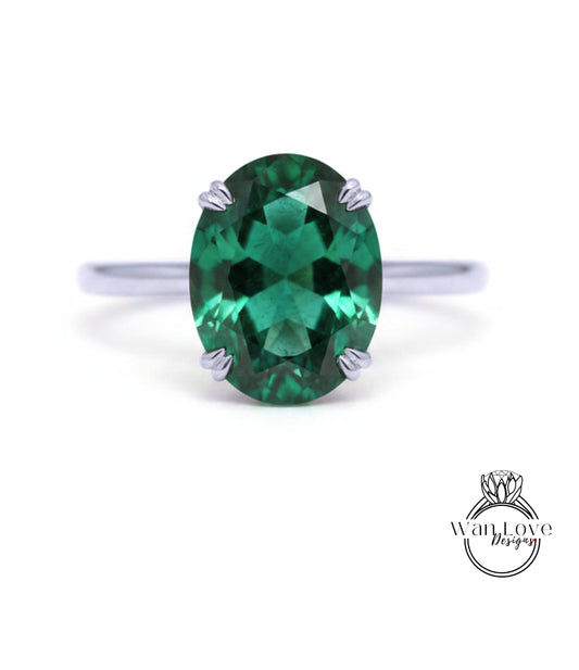 A close-up image of a silver ring with a large oval-shaped green gemstone, which appears to be a sapphire.